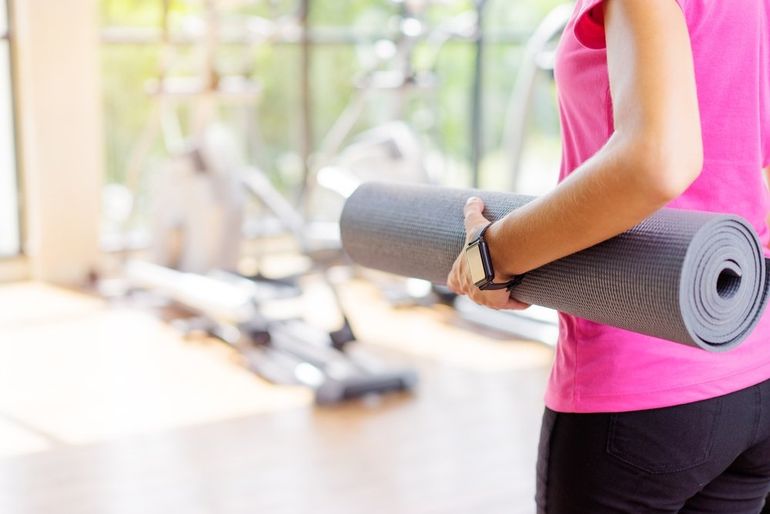 Donna in palestra con un tappetino