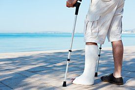 A man standing on crutches looking out to sea