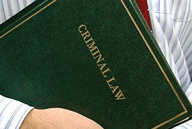 A leather folder entitled Criminal Law under a man's arm