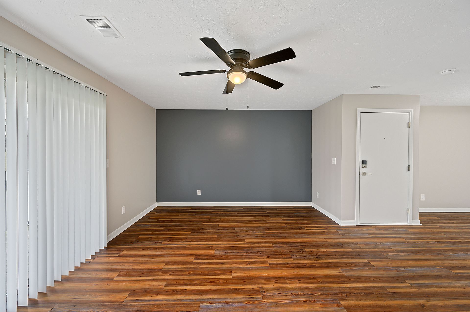 an empty living room with hardwood floors and a ceiling fan