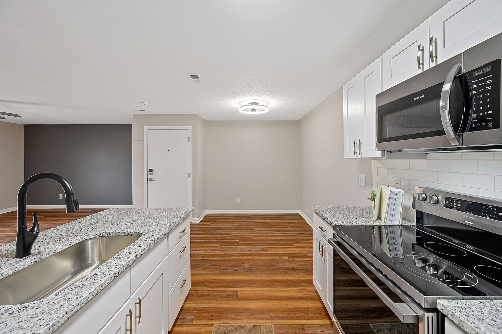 a kitchen with granite counter tops , stainless steel appliances , a sink , and a microwave .