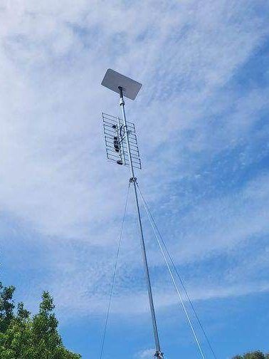 a large antenna is hanging from a pole in the sky .