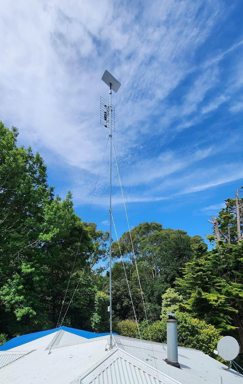 a satellite dish is sitting on top of a roof with trees in the background .
