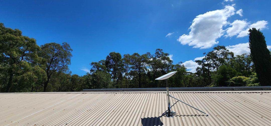 a satellite dish is sitting on top of a roof with trees in the background .