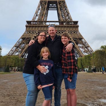 a family poses in front of the eiffel tower