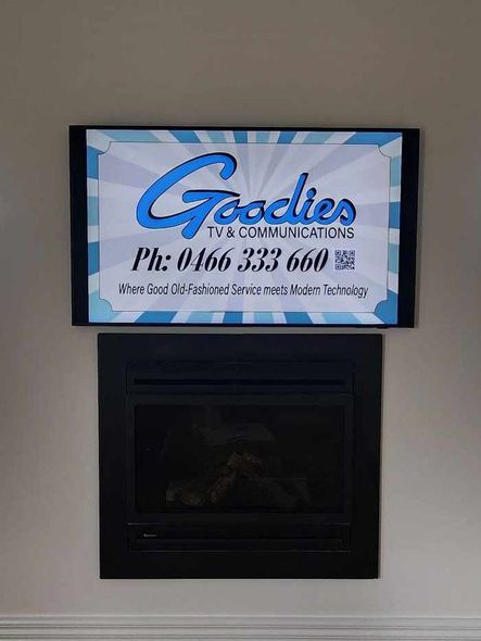 a fireplace with a sign above it that says goodies communications .