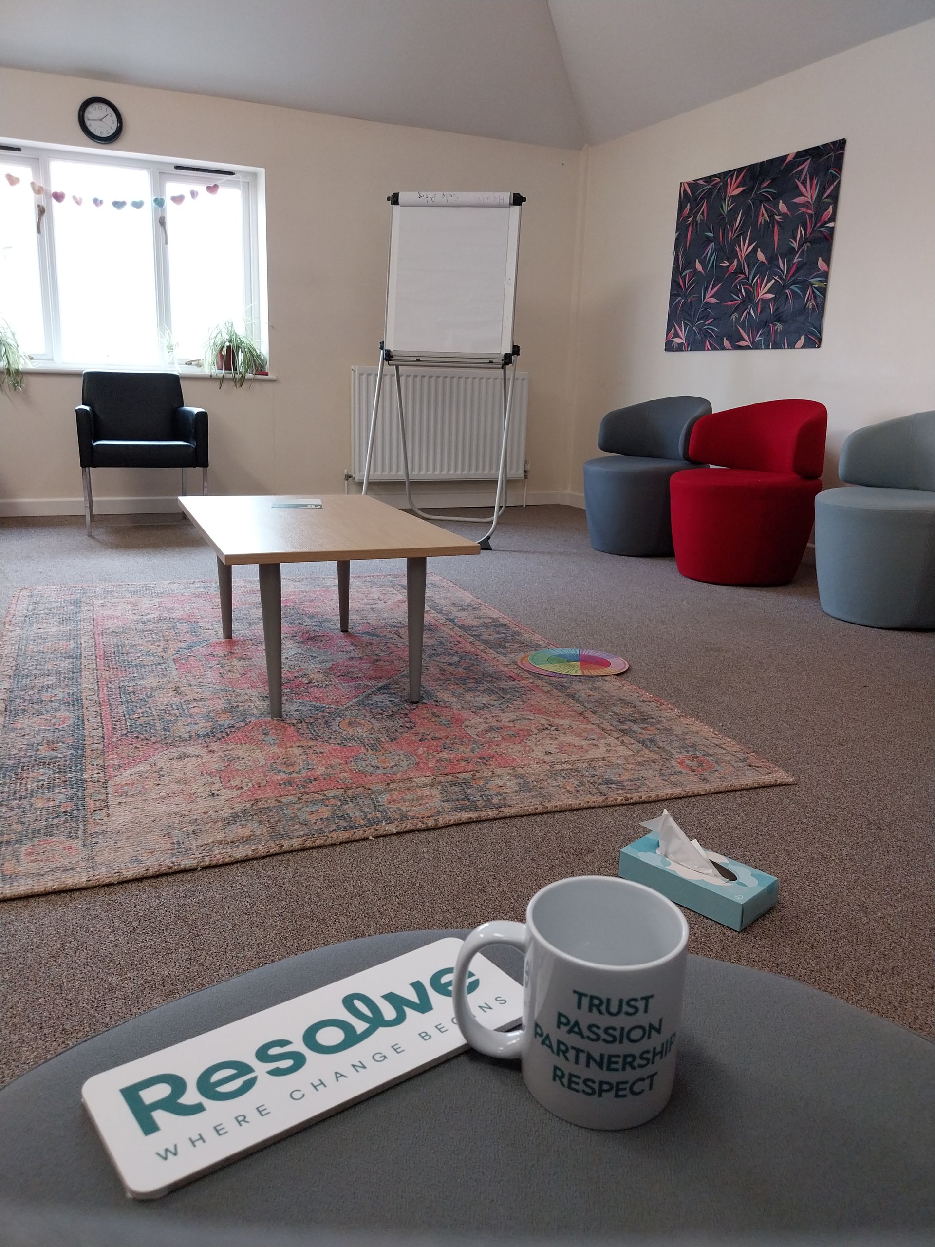 Three people walking on a dirt path in a wooded area, wearing jackets and backpacks.