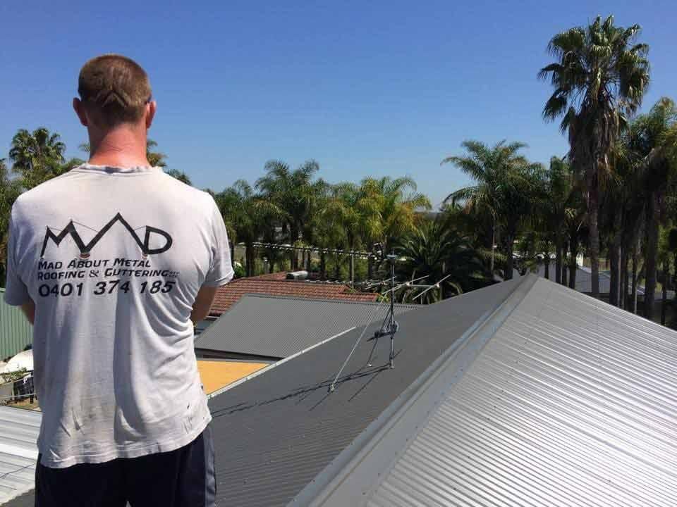 Man On Top Of A Grey Roof — Mad About Metal Roofing & Guttering PTY LTD in Newcastle, NSW