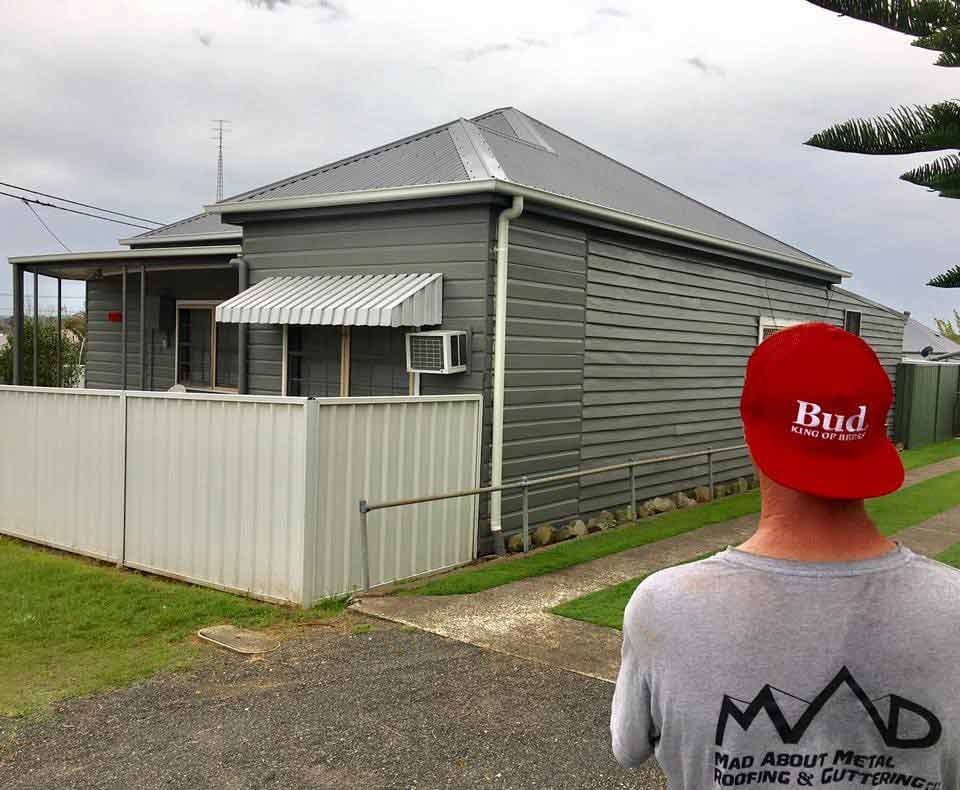Man With Red Cap Looking At The Newly Installed Roof — Mad About Metal Roofing & Guttering PTY LTD in Newcastle, NSW