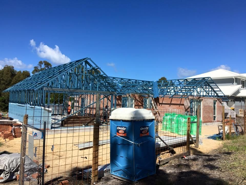 A Blue Portable Toilet Is Sitting In Front Of A Building Under Construction — Mad About Metal Roofing & Guttering PTY LTD in Newcastle, NSW