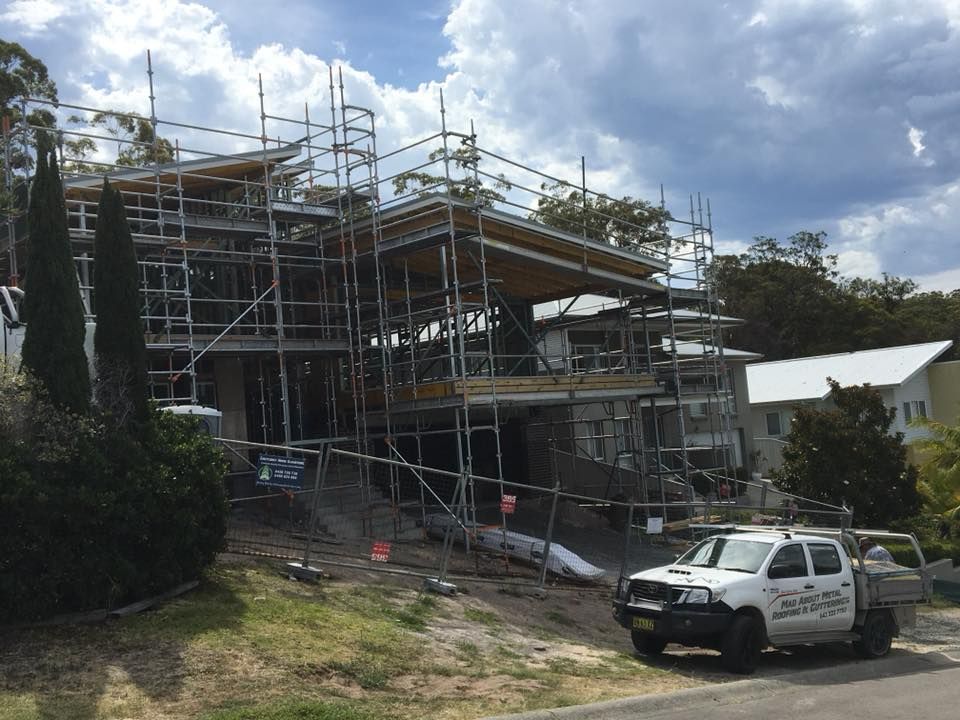 A White Truck Is Parked in Front of A Building Under Construction — Mad About Metal Roofing & Guttering PTY LTD in Newcastle, NSW