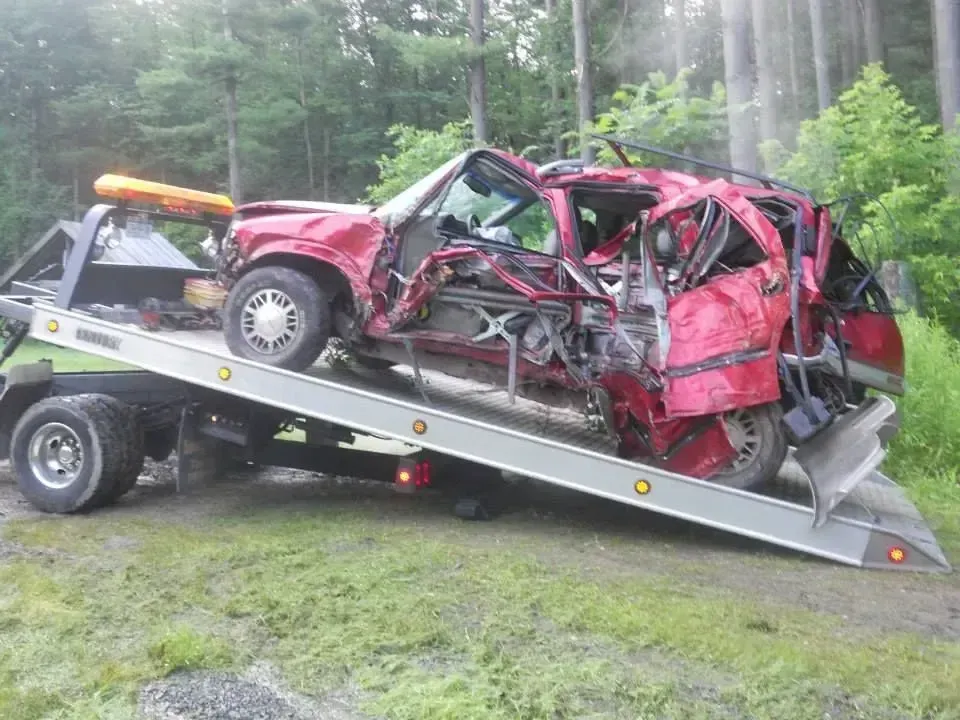 A wrecked car is being towed by a tow truck