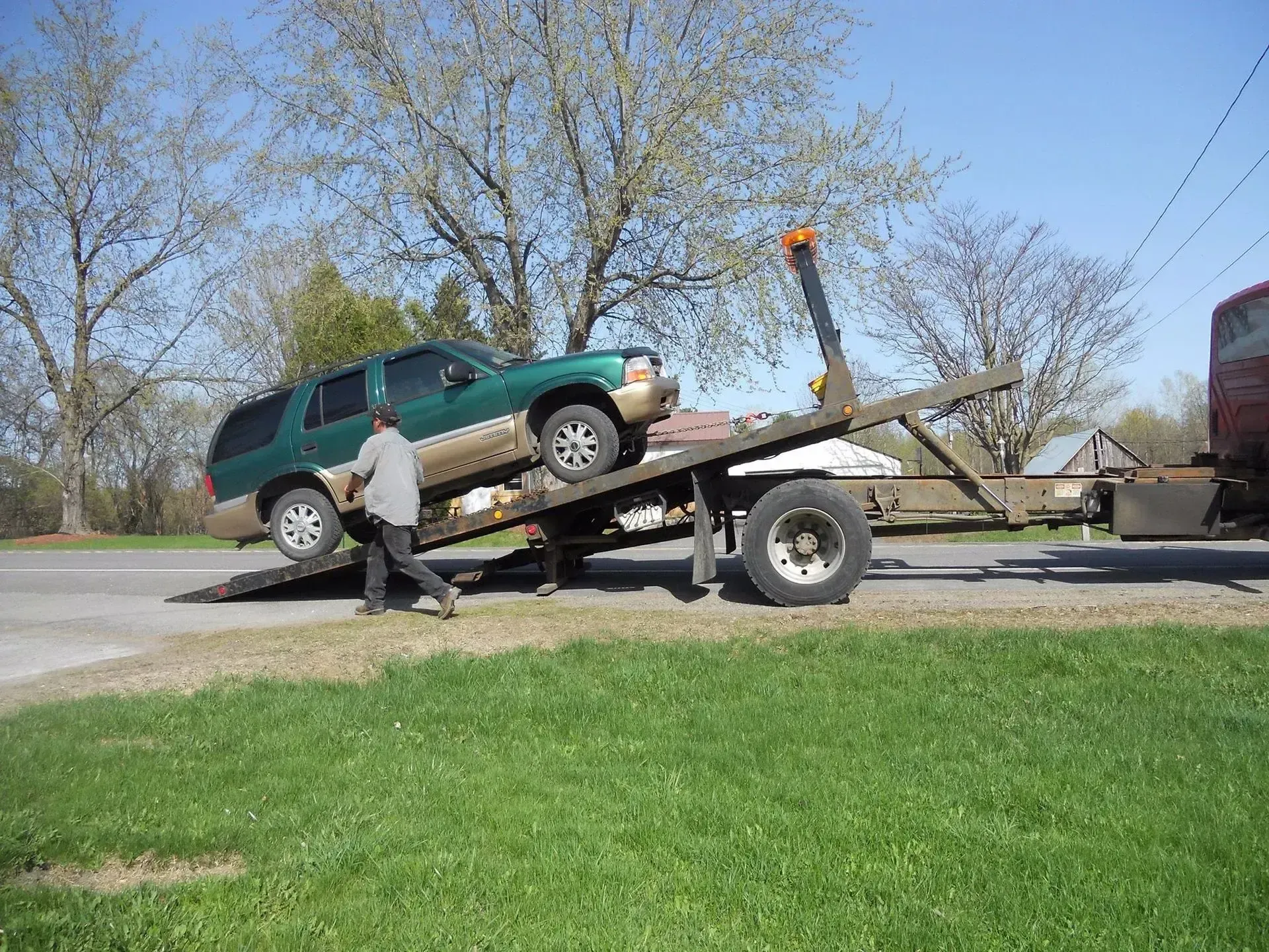 A green suv is being towed by a tow truck.