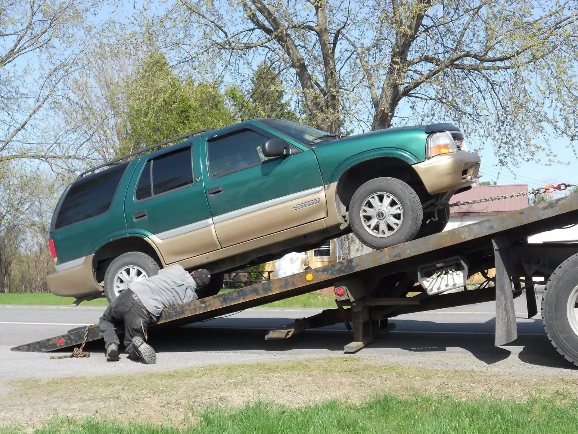 A green suv is being towed by a tow truck