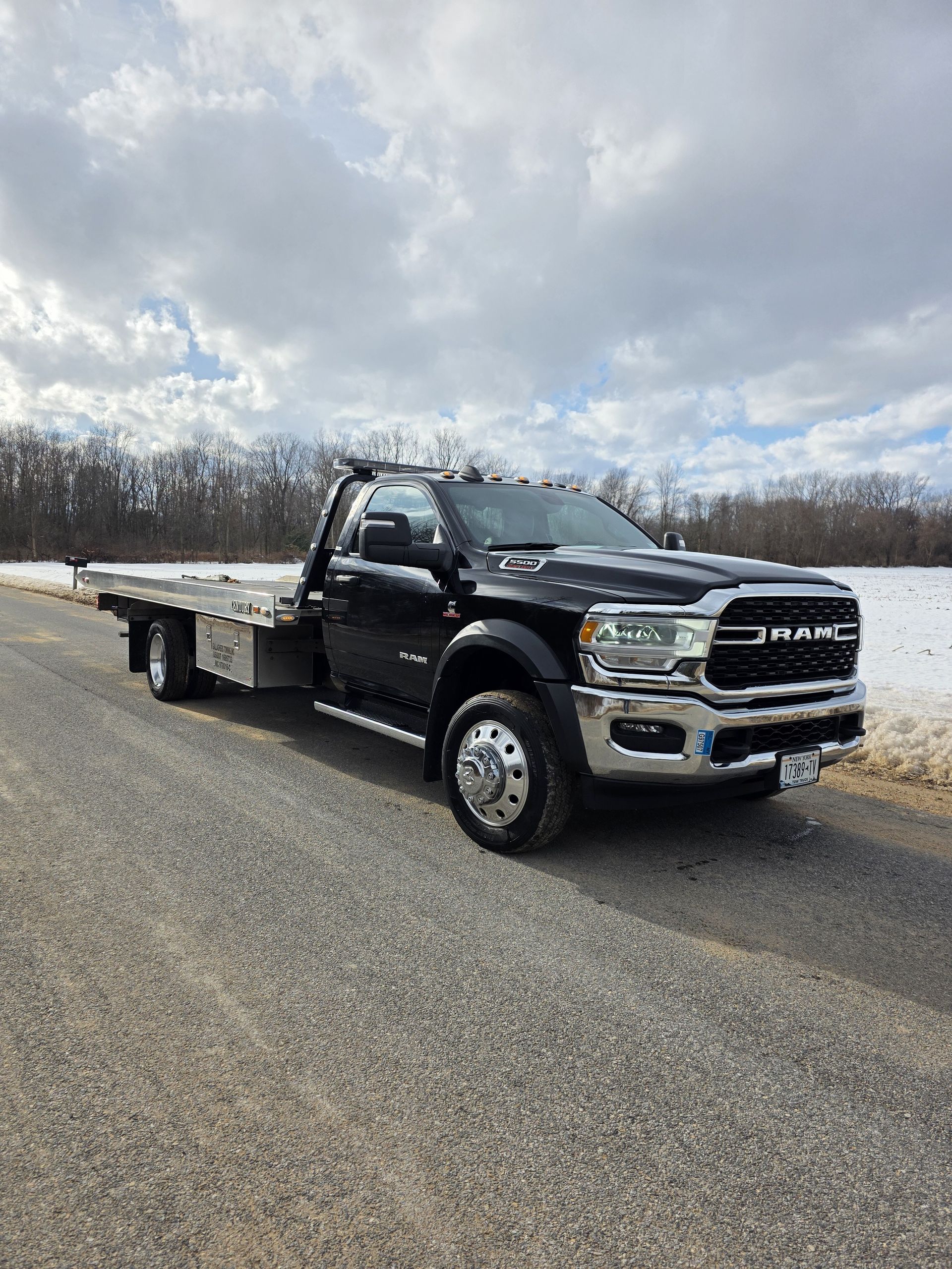 A black tow truck is parked on the side of a road.