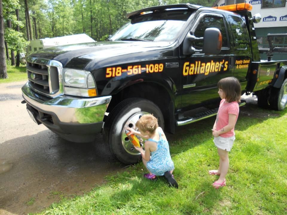 Two little girls looking at a gallagher 's tow truck