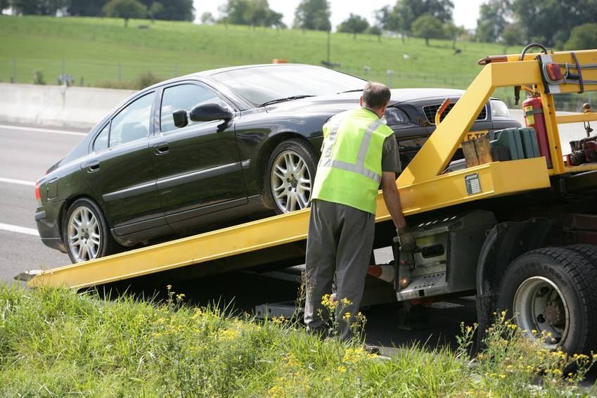 A man is loading a car onto a tow truck.