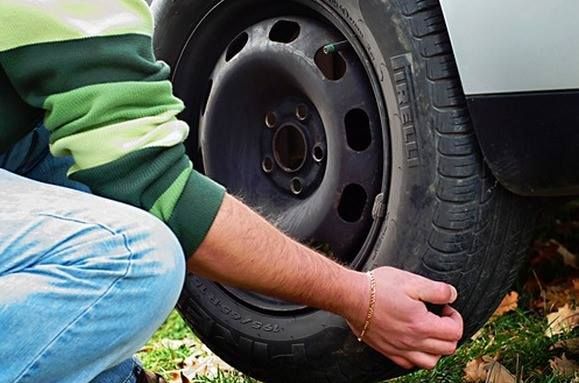 A man is changing a tire on a car