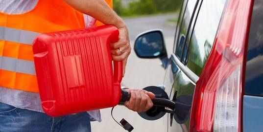 A man is pumping gas into a car while holding a red gas can.