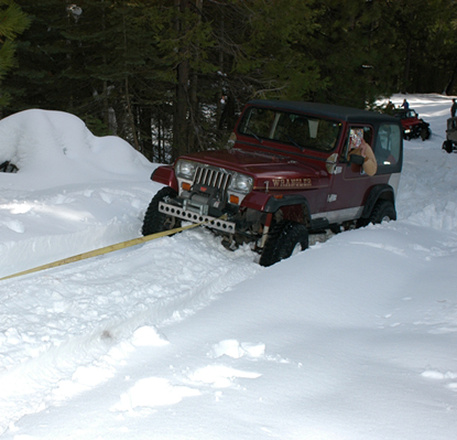 A red jeep is driving through a snowy forest