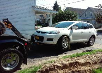 A white car is being towed by a tow truck.