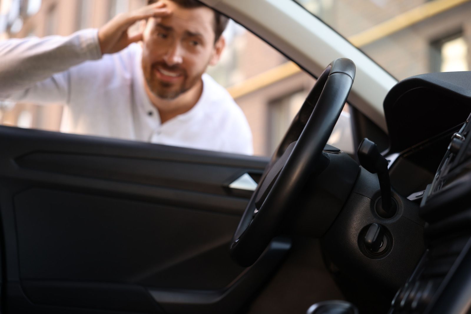 A man is looking through the window of a car.