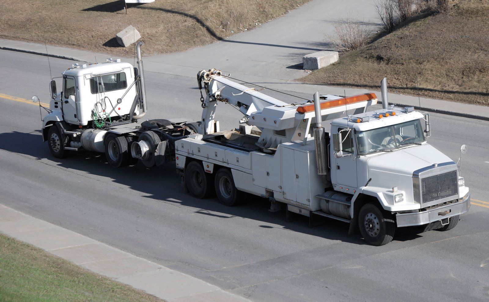 A white tow truck with a crane on the back of it