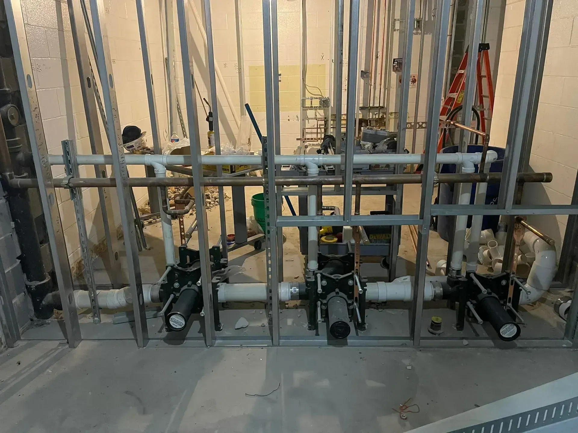 Plumbing pipes with black valves installed within a metal stud framework.