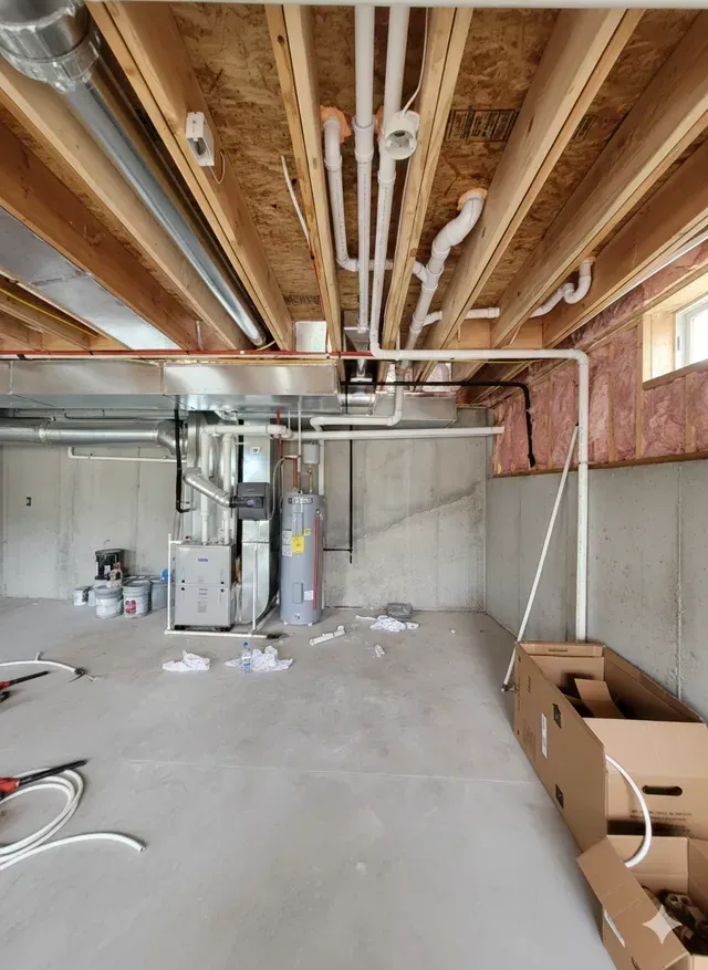 Basement with exposed pipes, HVAC, water heater, and framing. Unfinished concrete walls and floor.