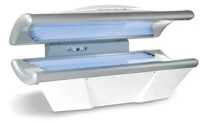 Tanning bed with blue UV lights and silver accents, white frame.