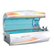 Tanning bed with white, curved body, blue lights, and orange accents, likely in a salon.