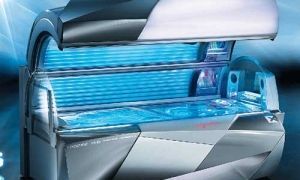 Tanning bed with blue UV lights. Silver and black interior, open and ready for use.