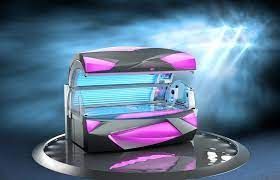Tanning bed, gray and pink, with blue UV lights, on a reflective surface, against a blue and white background.