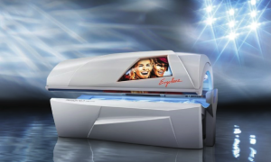 White tanning bed with blue lights, graphic of smiling faces, against a light-filled background.