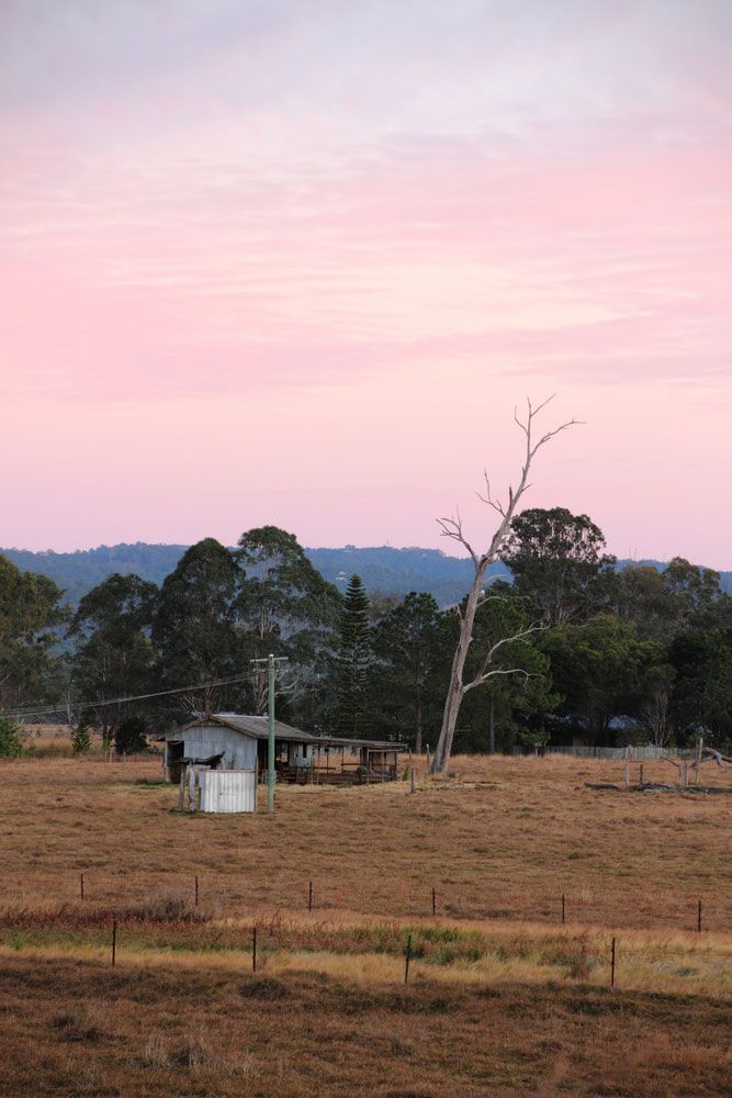 There Is A House In The Middle Of A Field With A Pink Sky In The Background — Unique By Nature Allied Health Service In Morayfield, QLD