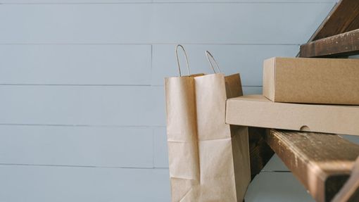 Una pila de cajas de cartón y bolsas de papel en un banco de madera.