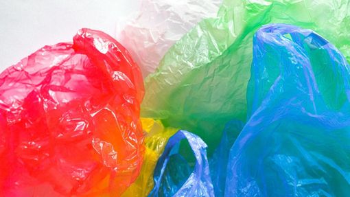 Una pila de bolsas de plástico de colores sobre una superficie blanca.
