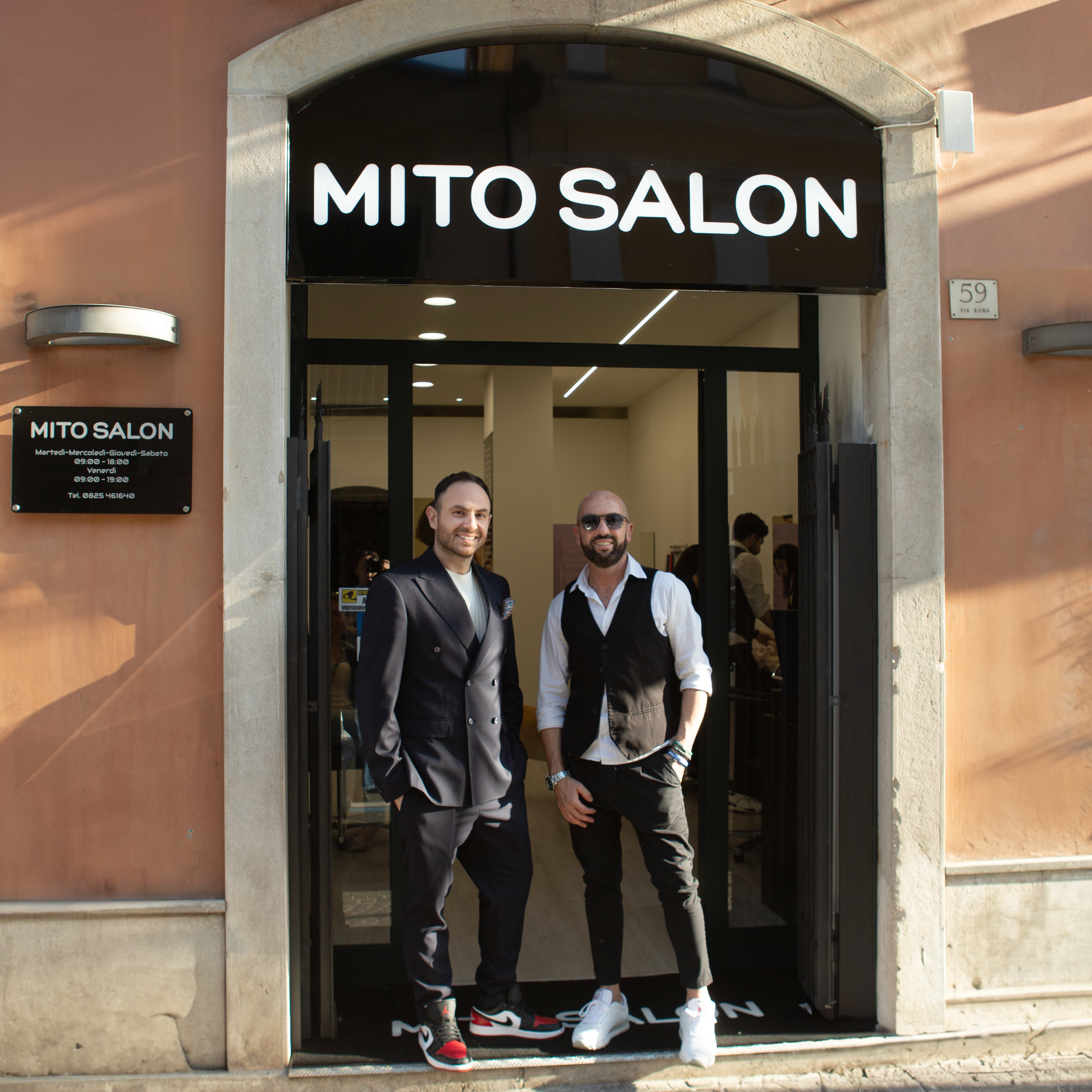 Due uomini in piedi all'ingresso del negozio MITO SALON