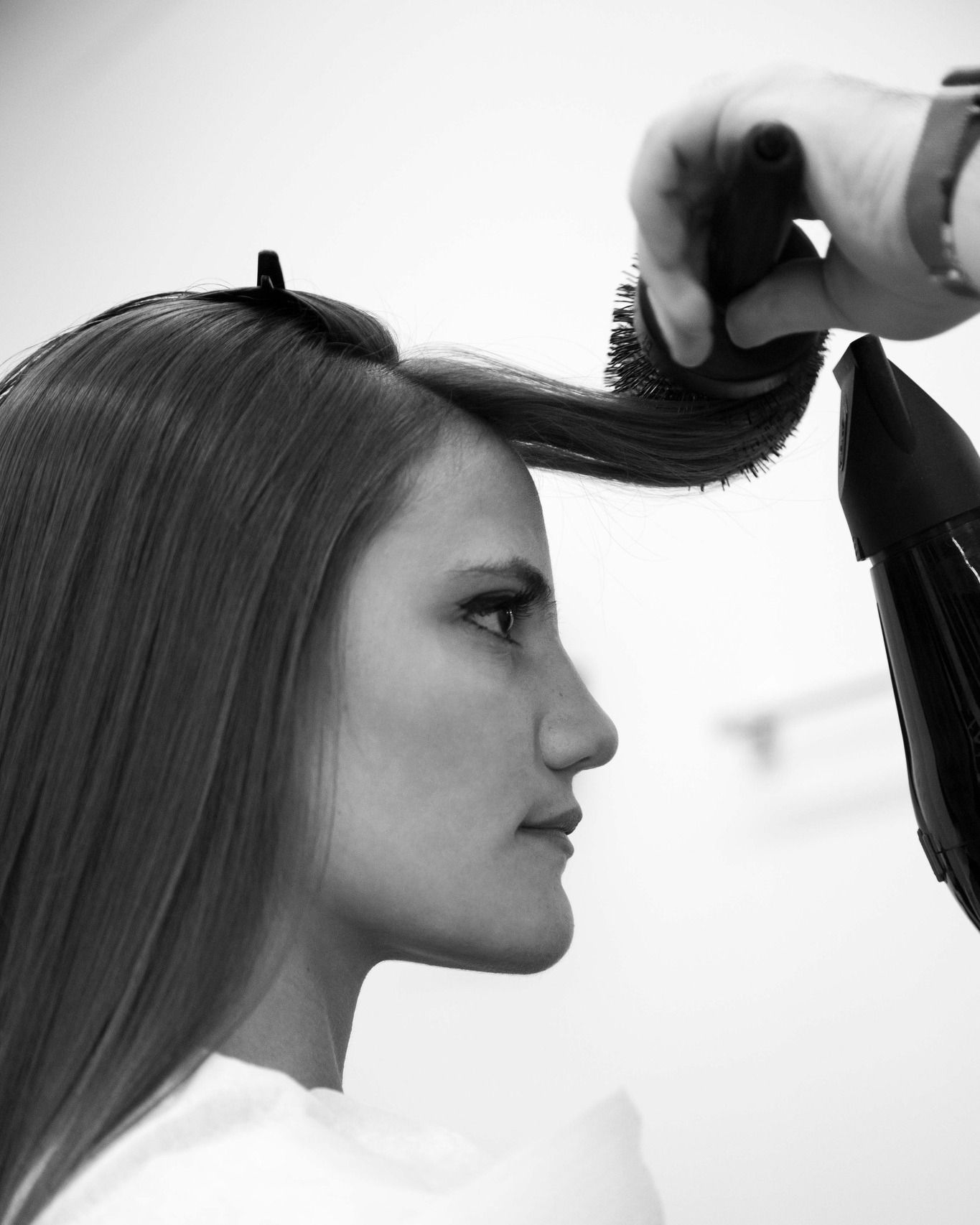 Una donna si fa dividere i capelli in sezioni da un parrucchiere con un pettine, in bianco e nero.