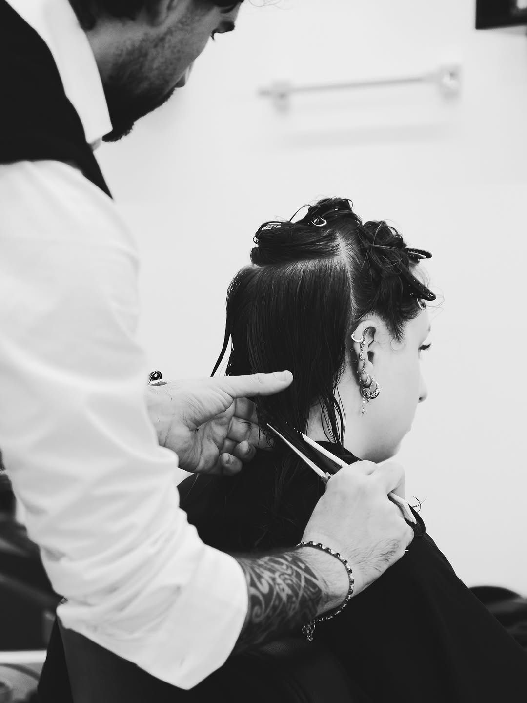 Parrucchiere che taglia i capelli a una cliente su una poltrona da salone, scena in bianco e nero