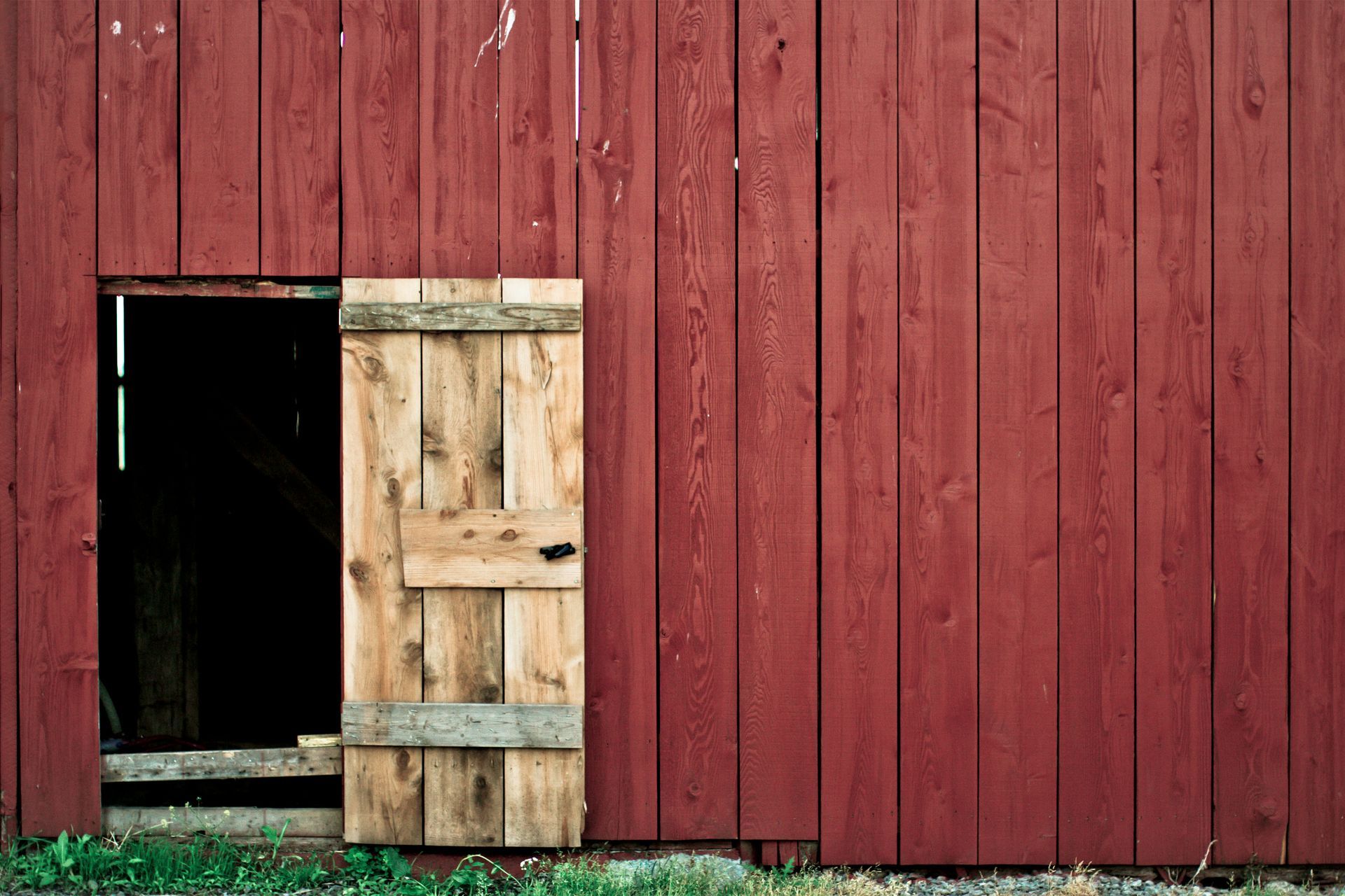 A red barn with a wooden door open.