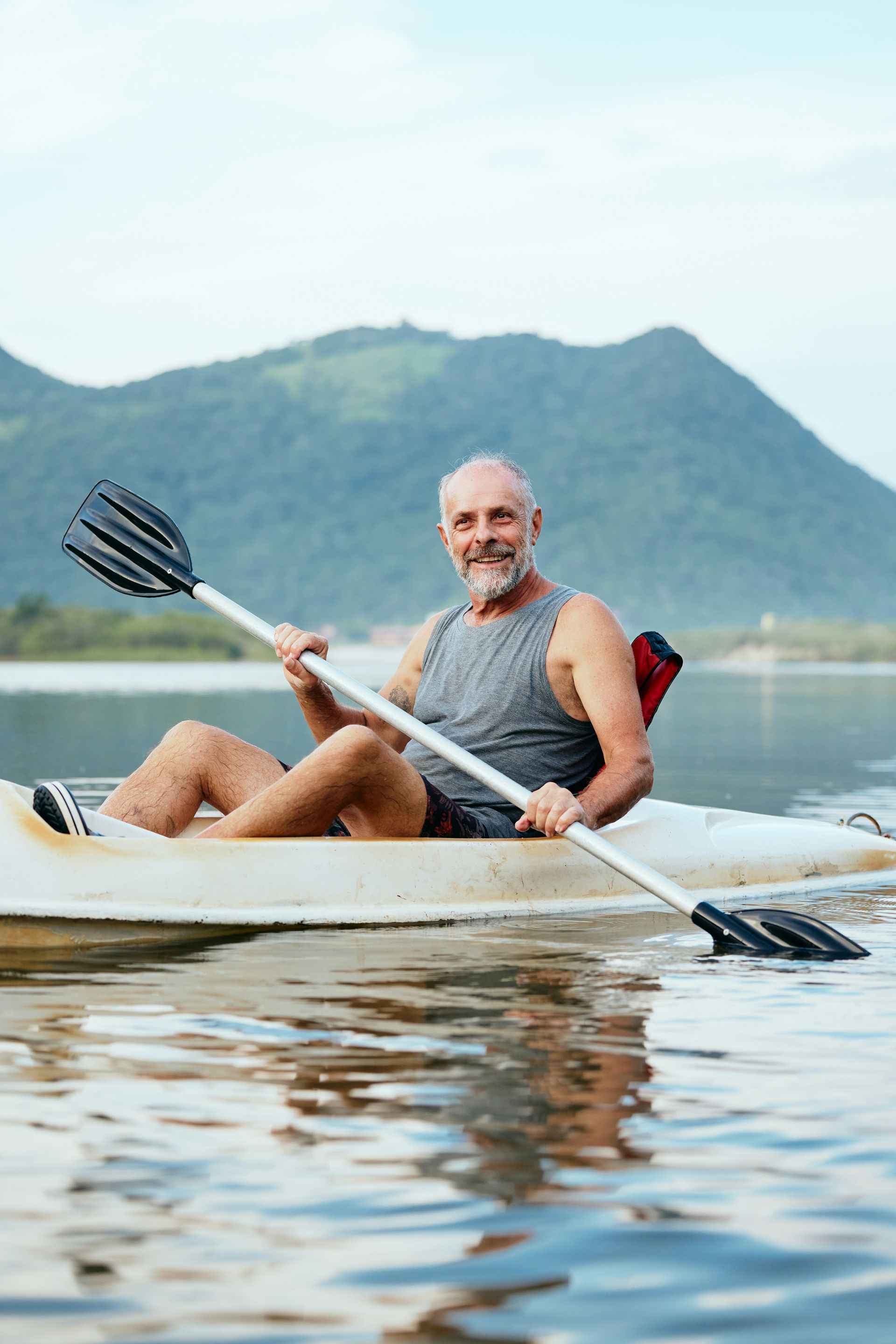 A man is paddling a kayak on a lake.