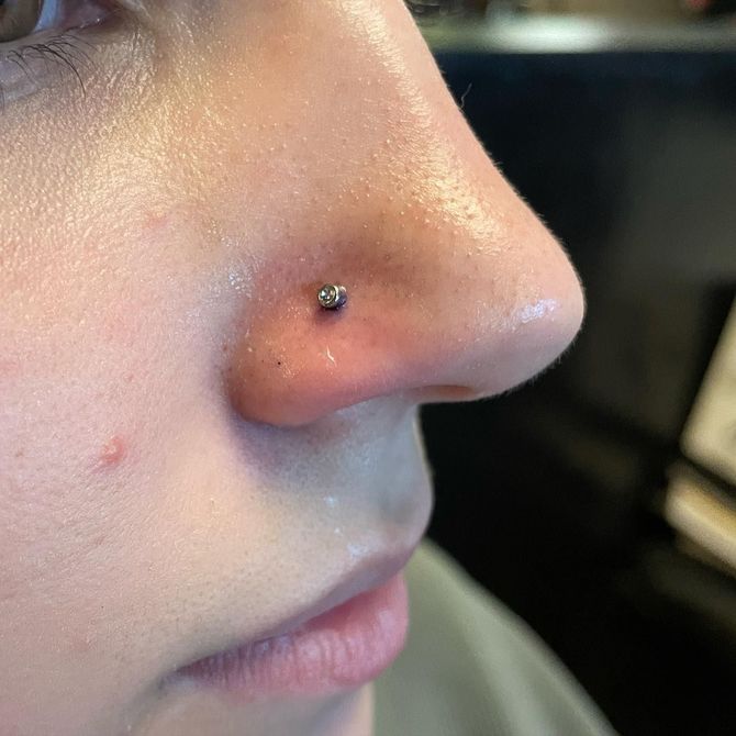 A close up of a woman 's nose with a nose ring.