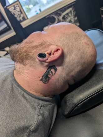 A man is laying down with a tattoo on his neck.