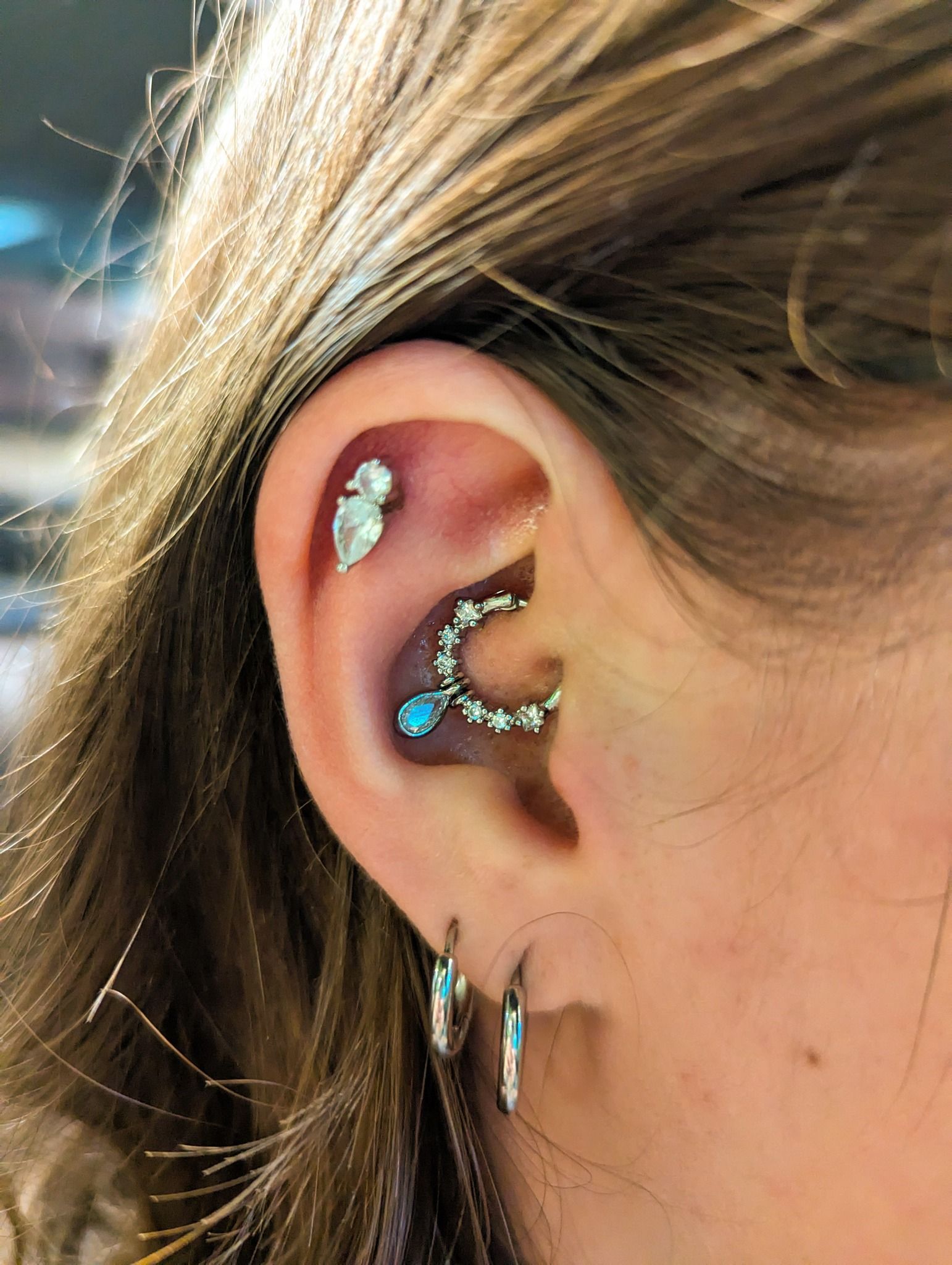 A close up of a woman 's ear with multiple piercings