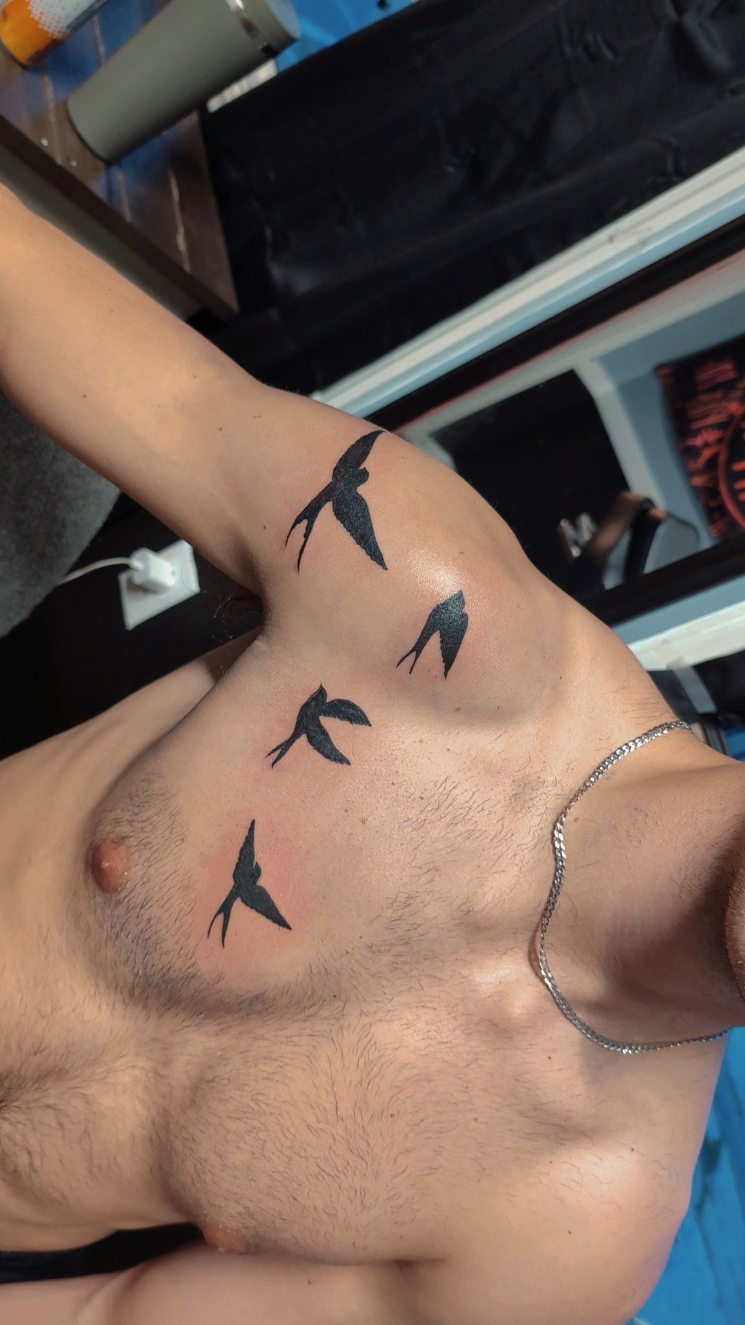 A man has a tattoo of four birds on his chest.