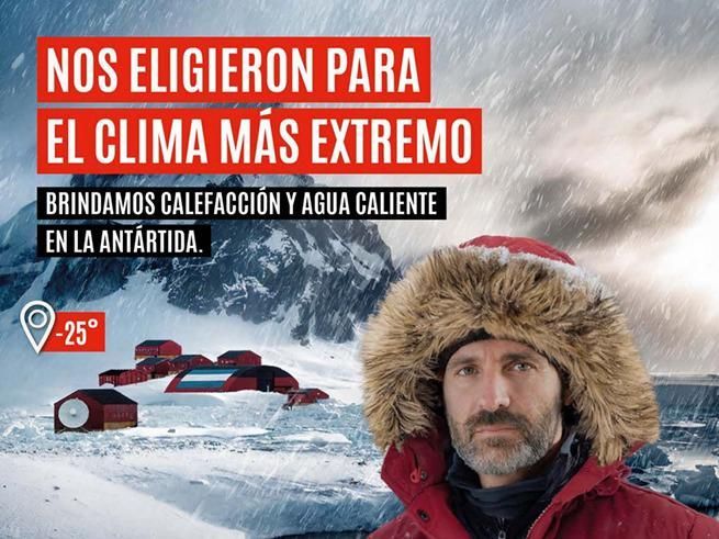 Un hombre con ropa de invierno frente a edificios antárticos cubiertos de nieve