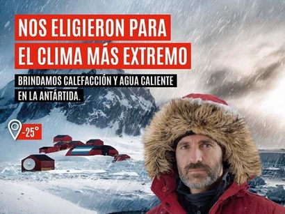 Un hombre con ropa de invierno frente a edificios antárticos cubiertos de nieve