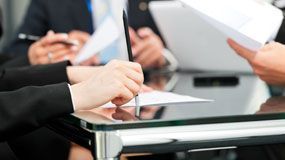 A lawyer is sitting at a desk writing in a notebook.