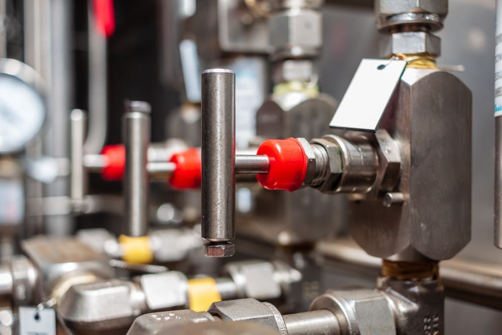 A Row Of Stainless Steel Pipes With Red Handles In A Factory — CG Plumbing & Drainage In Singleton, NSW